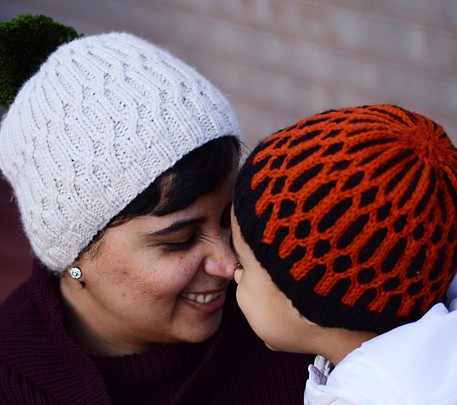 Free knitting patterns for Uljhan Hats - This fun beanie features a play on a 2x2 rib, using two colors of yarn. It also uses a 1x1 cable at specified intervals, to form a pretty pattern over the body of the beanie.